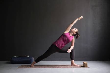 A woman doing yoga on a mat showing the extended side angle