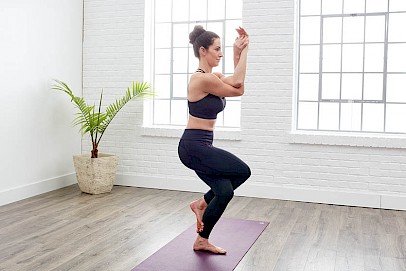 A woman doing yoga at home performing the Eagle Pose move