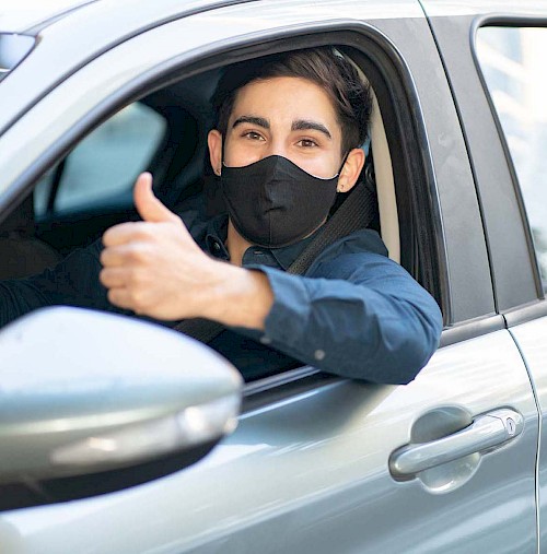 A young man with a face covering getting drive through tested at his local HealthCare Express Urgent Care location.