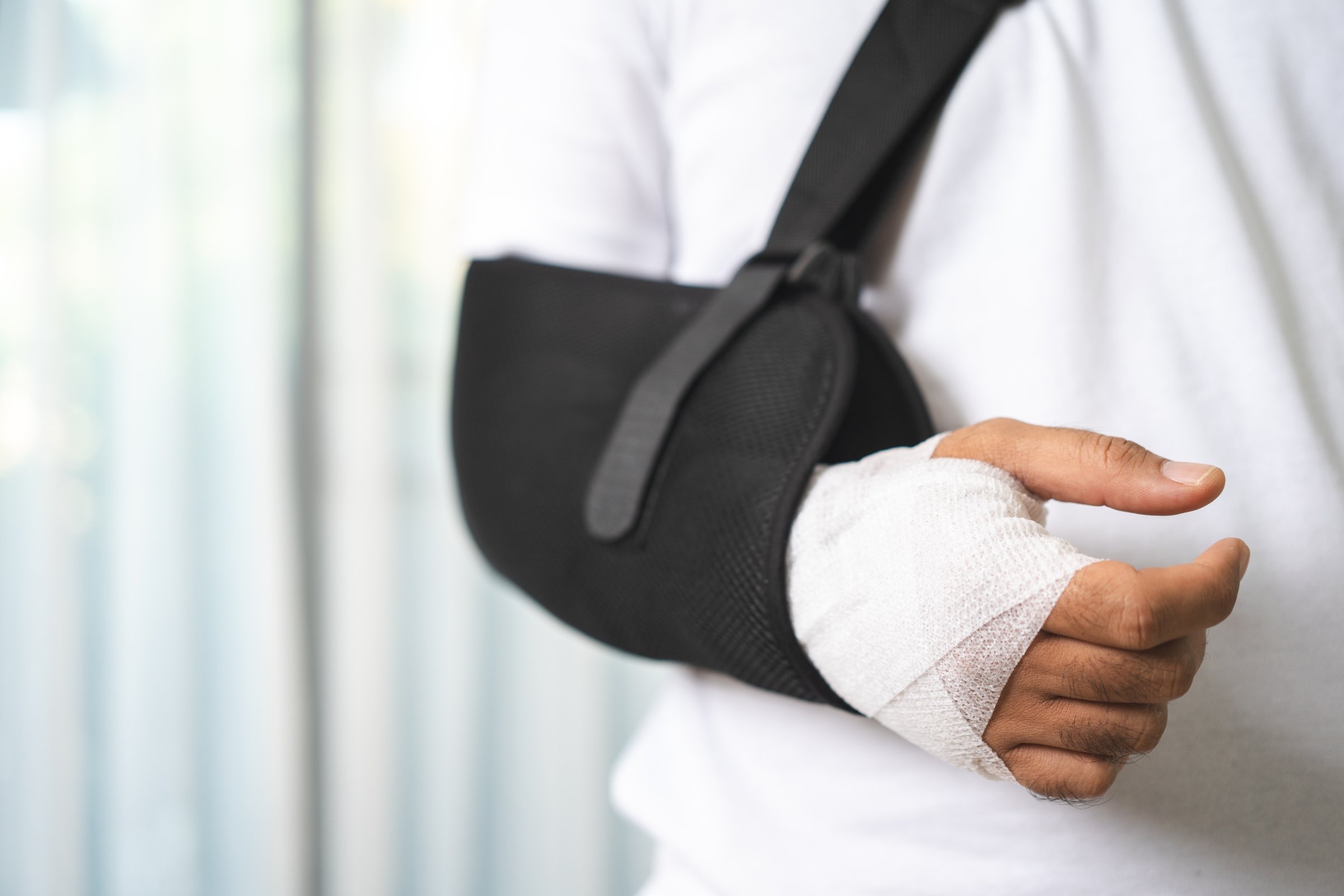Patient with an arm in a sling and a bandaged hand