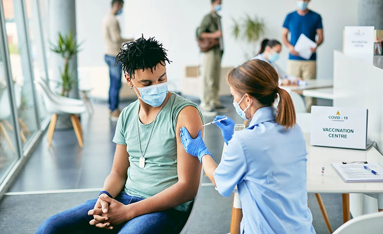 A nurse giving a young man a vaccine